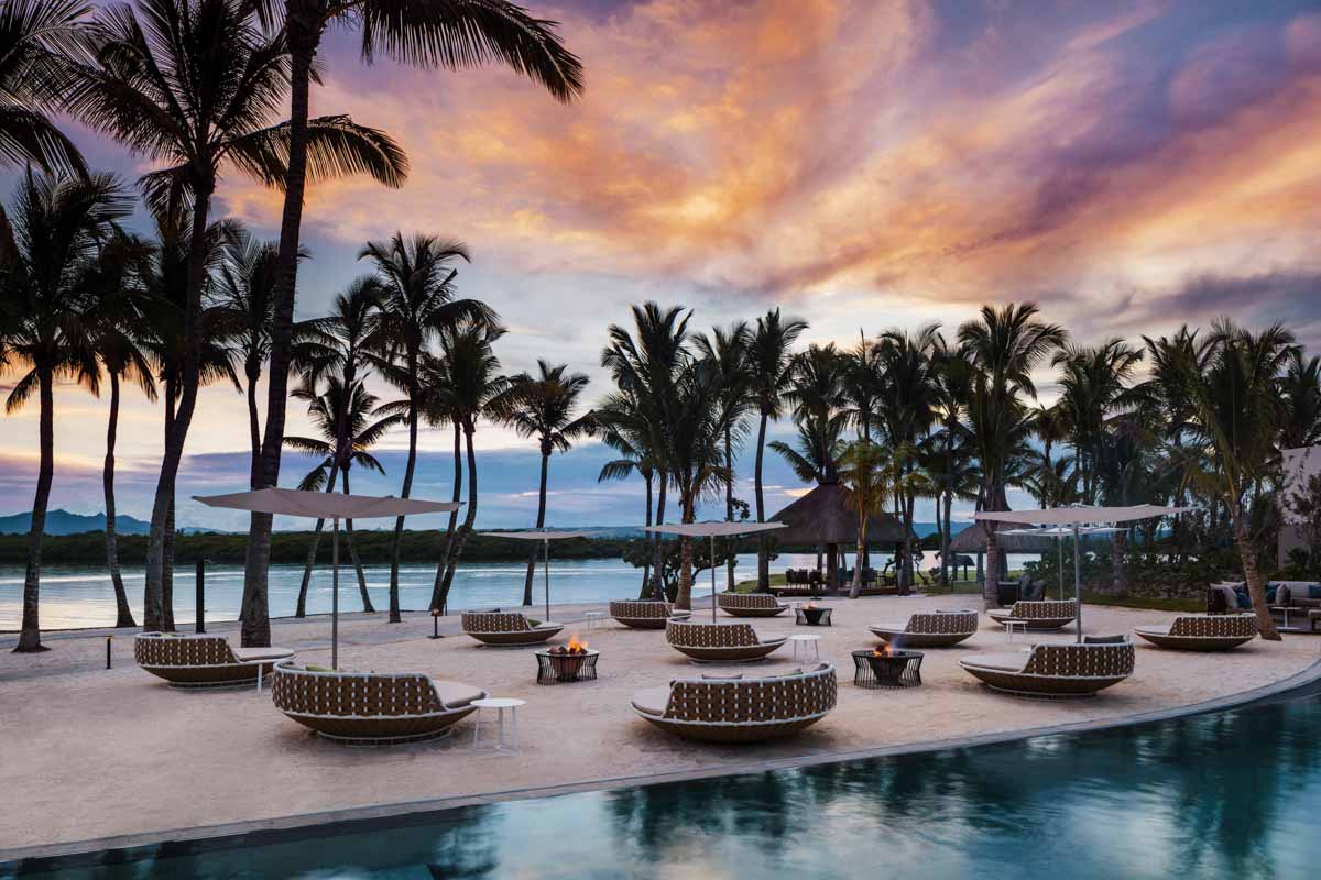 A pool with lounge chairs and palm trees in the background.
